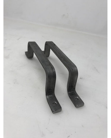 Two black wrought iron Onondaga door handles by Industrial Farm Co with curved design and mounting holes on white marble s...