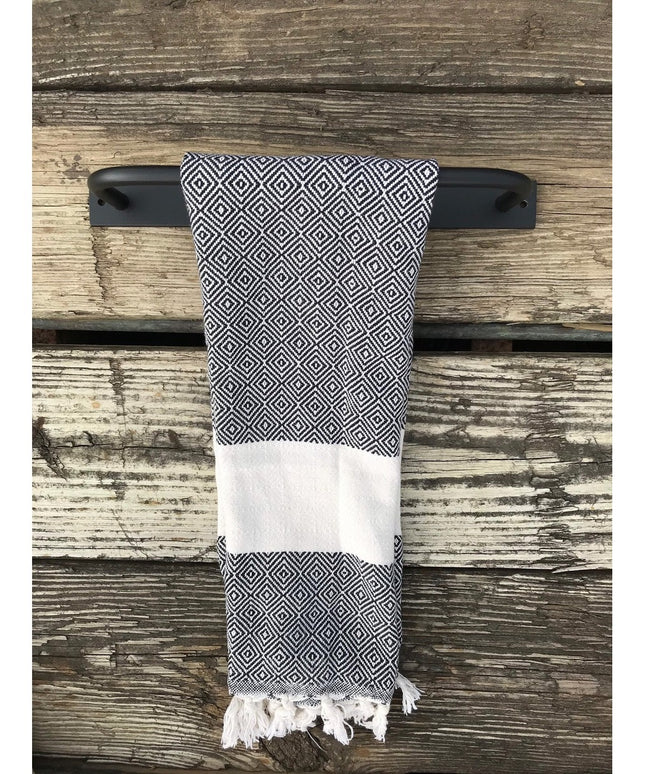 Black metal Oswego Modern Bathroom Towel Bar by Industrial Farm Co mounted on weathered wood with geometric patterned towel