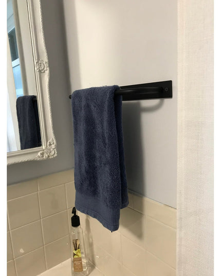 Black matte Oswego Modern Bathroom Towel Bar by Industrial Farm Co mounted on white wall with navy blue towel and ornate m...
