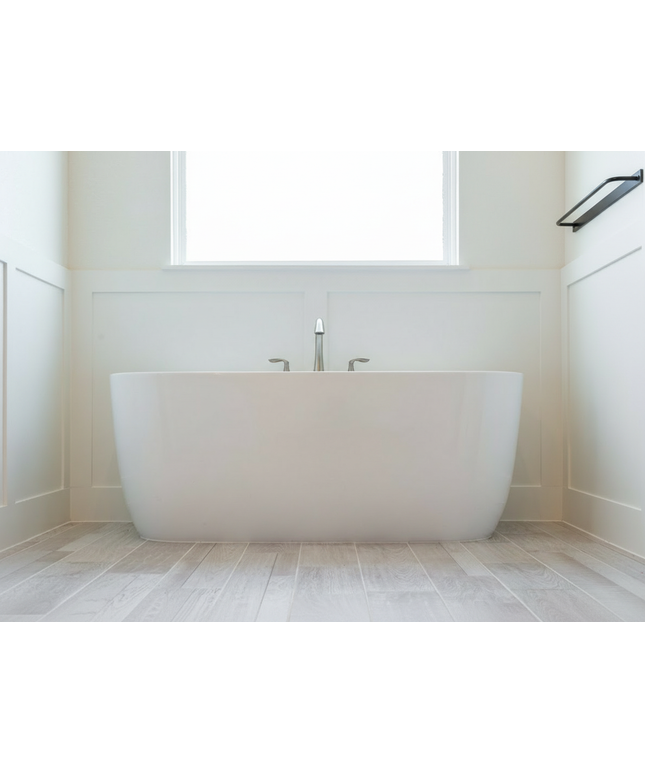 Modern white freestanding bathtub in a minimalistic bathroom with a window above.