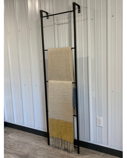 The Hal Standing Mounted Blanket Ladder in black metal with cream and yellow throw blanket, wall-mounted design by Industr...