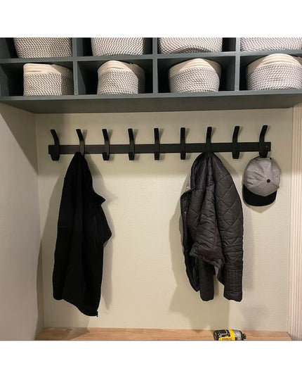 Black metal Christopher Double Hook Coat Rack by Industrial Farm Co mounted on white wall with baskets above, holding dark...