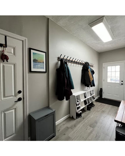 Black metal Christopher Double Hook Coat Rack by Industrial Farm Co mounted on mudroom wall with coats hanging, white shoe...