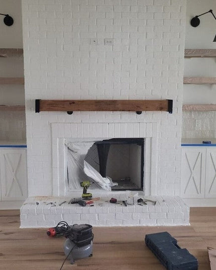 White painted brick fireplace with wooden mantel beam and built-in cabinets featuring Vandiver Evergreen Tree Mantel End C...
