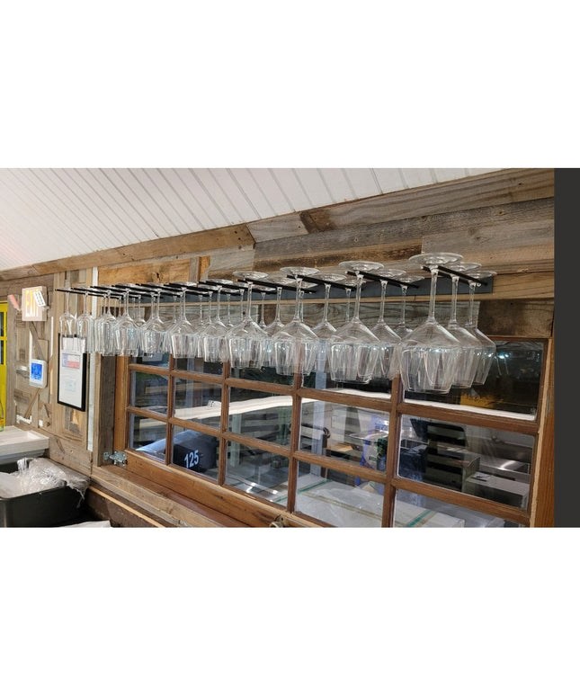 White Plains Wine Glass Rack by Industrial Farm Co mounted under rustic wooden beams holding multiple wine glasses in mode...