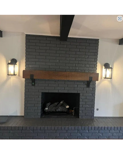 Black brick fireplace with wooden mantel supported by heavy duty steel Spafford brackets with rivets from Industrial Farm Co