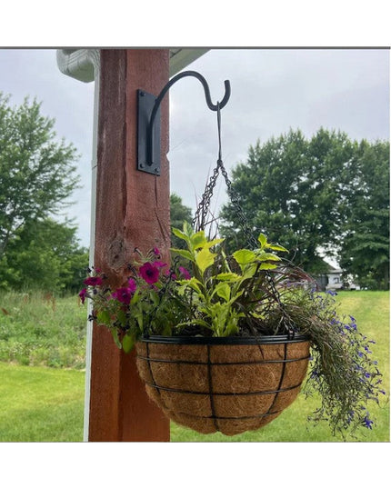 Black metal Gregory Shepherd Hook by Industrial Farm Co mounted on wooden post holding wire basket with colorful flowering...