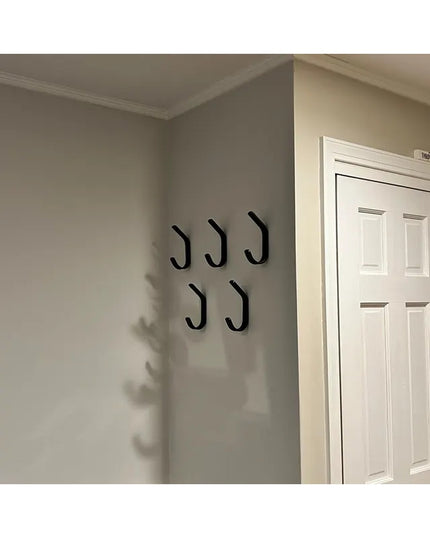 Five black metal double hooks mounted on gray wall next to white door - The Henrietta 1" Wide Double Hook by Industrial Fa...