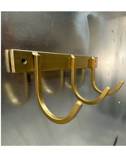Gold metal wall-mounted key rack with 4 U-shaped hooks by Industrial Farm Co, showing modern rustic design on concrete wall
