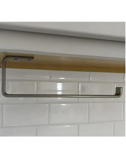 The Jordan Paper Towel Holder by Industrial Farm Co mounted under cabinet with stainless steel finish against white subway...