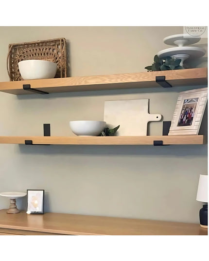 Black metal J-style shelf brackets supporting natural wood floating shelves with decorative bowls and home decor items on ...