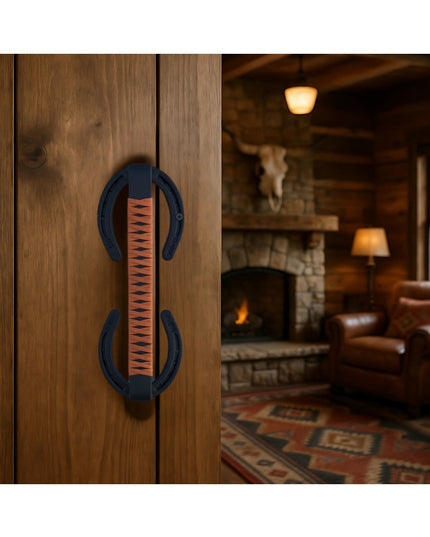 Bermuda Horseshoe Door Handle with black leather wrap mounted on wooden doors, rustic cabin interior with fireplace in bac...