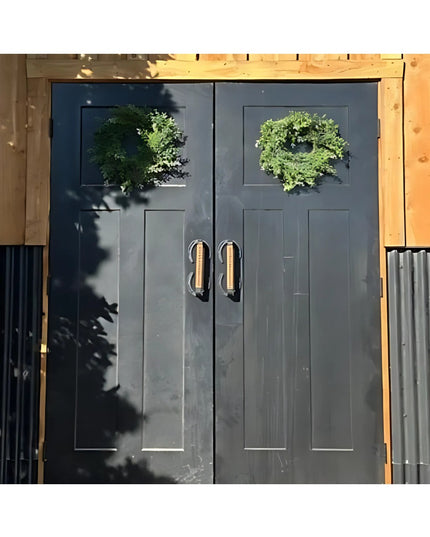 Dark gray double doors with Bermuda Horseshoe leather-wrapped door handles by Industrial Farm Co, featuring green wreaths ...