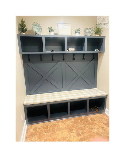 Gray farmhouse mudroom bench with built-in storage cubbies, decorative X-panel doors, wall-mounted shelving, and black met...
