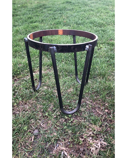 Black metal Dorio Raised Planter by Industrial Farm Co with circular rim and curved legs on grass outdoor setting