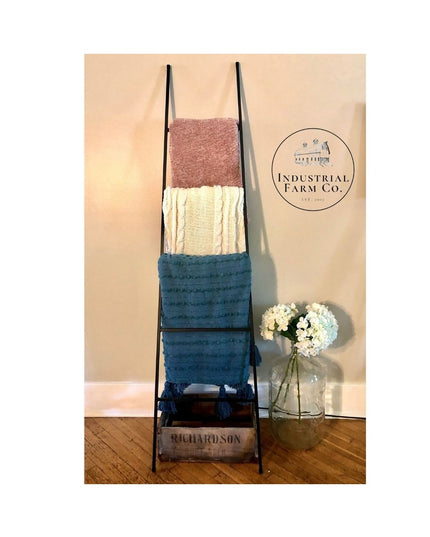 Black tapered farmhouse ladder by Industrial Farm Co displaying colorful textured throws in coral, cream and blue tones wi...