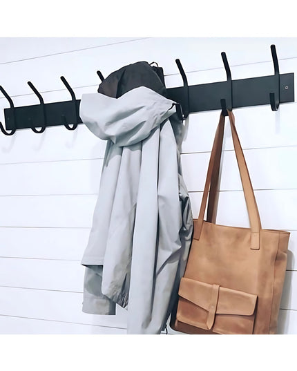Black metal Cooperstown Double Hook Coat Rack mounted on white shiplap wall with gray coat and tan leather handbag hanging
