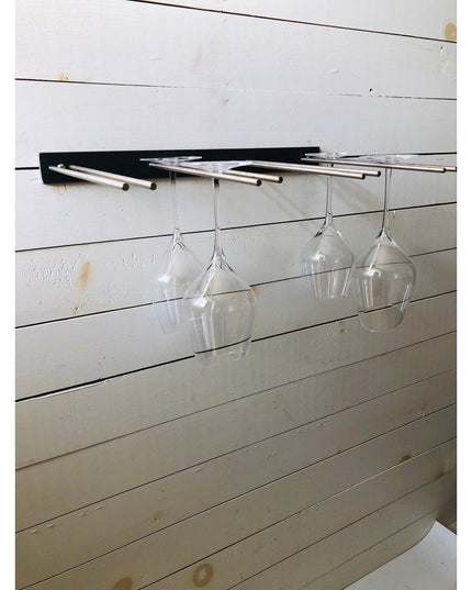 White Plains Wine Glass Rack by Industrial Farm Co mounted on white shiplap wall with black bracket holding four clear win...