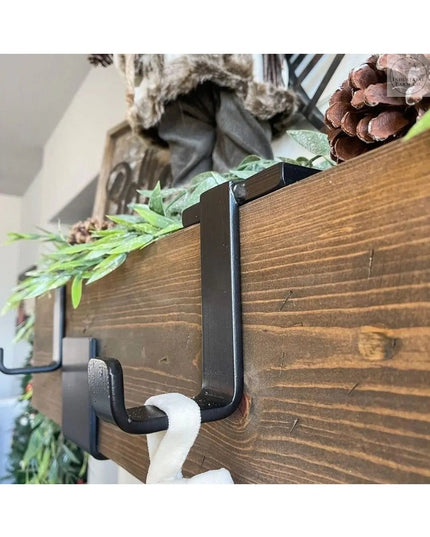 The Annie Stocking Holder by Industrial Farm Co - black metal hook mounted on rustic wood mantel with white stocking and h...