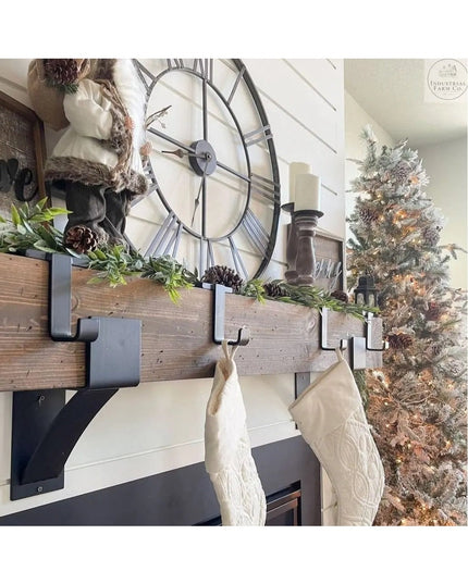 Industrial Farm Co Annie Stocking Holder in black metal mounted on rustic wood mantel with Christmas stockings and holiday...