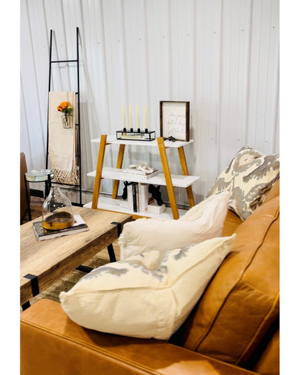 Black metal tapered farmhouse ladder by Industrial Farm Co displayed in cozy living room with orange leather sofa and whit...