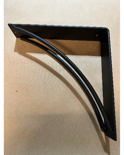 Black metal Sawmiller shelf bracket by Industrial Farm Co with curved triangular support design casting shadow on beige su...