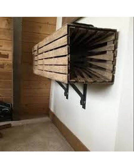 Black metal Butch Shelf Supports by Industrial Farm Co holding wooden crate shelves mounted on white wall in rustic interior