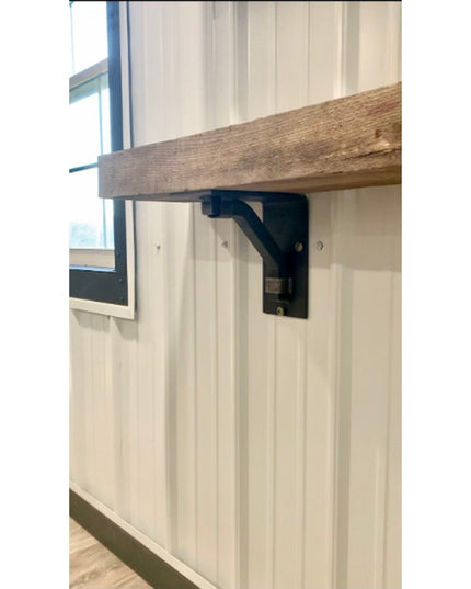 Black metal Rosamond shelf bracket supporting rustic wood shelf on white beadboard wall in farmhouse kitchen by Industrial...