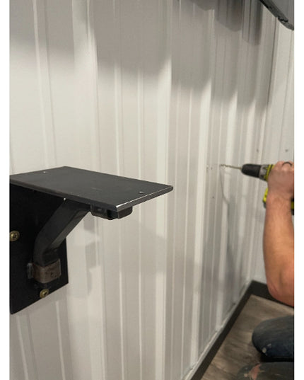 Black metal Rosamond Shelf Supports by Industrial Farm Co mounted on white wall with person installing using drill