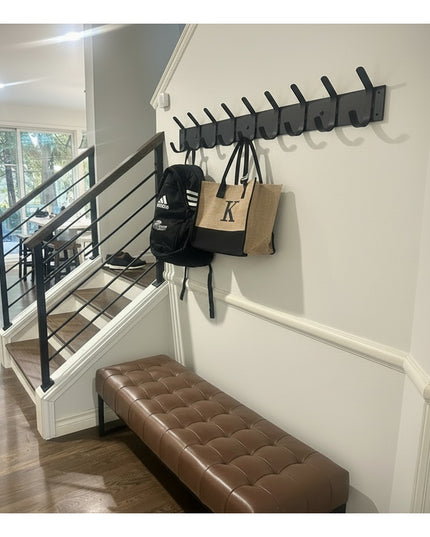 Riseform black metal wall mounted coat rack with multiple hooks installed in modern entryway with brown leather bench and ...