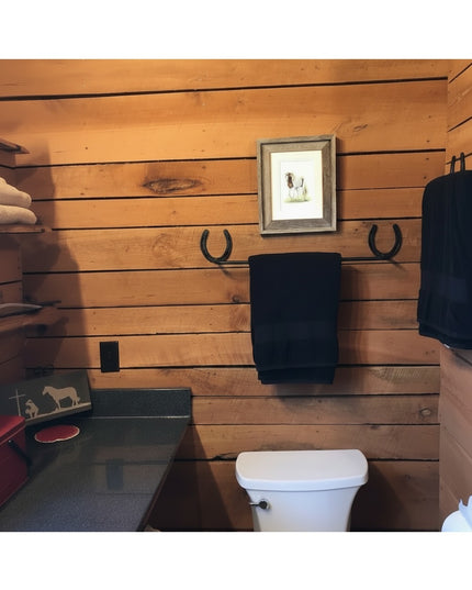 Black horseshoe towel bar mounted on rustic wood wall holding dark towel - The Donahue Horseshoe Blanket & Towel Bar by In...