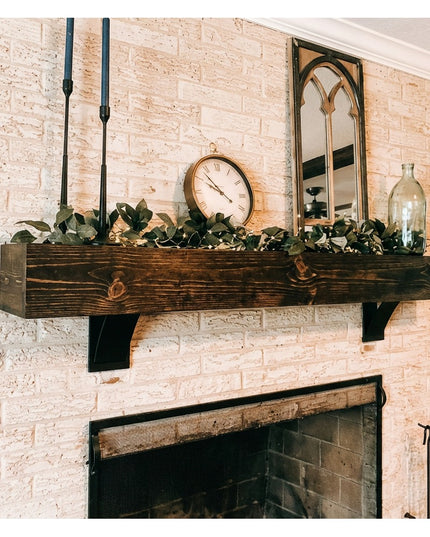 Black steel Industrial Farm Co Ninemile 5" shelf brackets supporting rustic wood mantel with greenery above white brick fi...