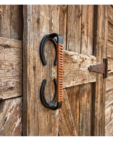 Bermuda Horseshoe Door Handle with brown leather wrap mounted on rustic weathered wood barn door by Industrial Farm Co