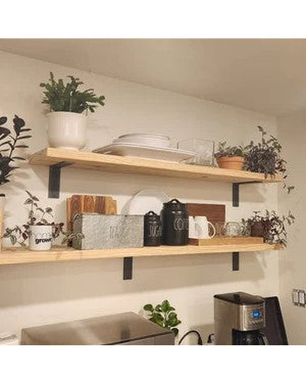 Black metal L-shaped shelf brackets supporting natural wood floating shelves in modern farmhouse kitchen with plants and d...