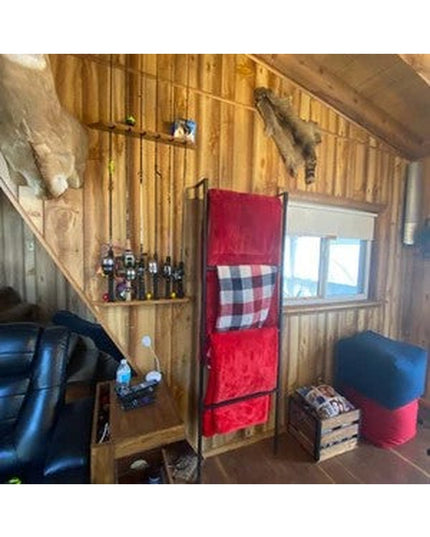 The Veronica Modern Blanket Ladder by Industrial Farm Co displaying red quilted blankets in rustic cabin interior with woo...