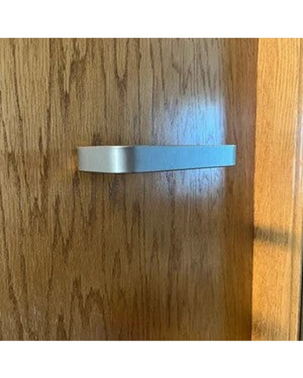 Modern brushed silver Emma towel holder door pull mounted on natural wood grain cabinet door by Industrial Farm Co