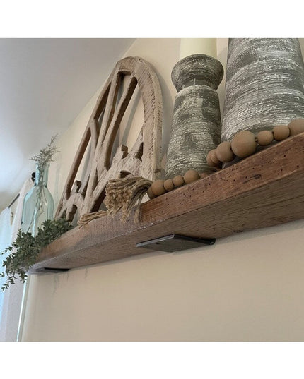 Heavy duty black steel L-shaped shelf brackets supporting rustic wood floating shelf with decorative farmhouse items and r...