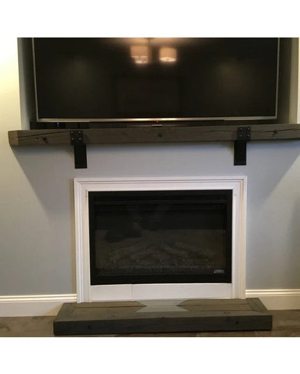 Black steel Spafford 3-inch mantel brackets with rivets mounted on dark wood beam above white fireplace, handmade by Indus...