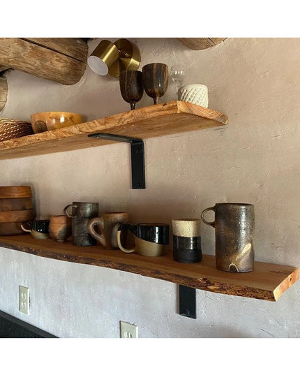 Black metal L-shaped shelf brackets supporting rustic wooden shelves displaying ceramic mugs and pottery in modern farmhou...