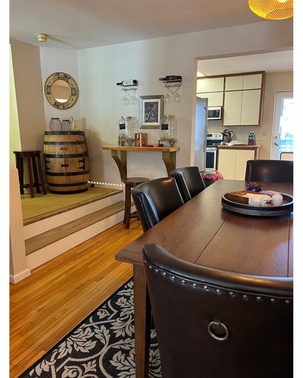 Rustic wooden console table with dark metal brackets supporting wine bottles and glassware in modern dining room with barr...