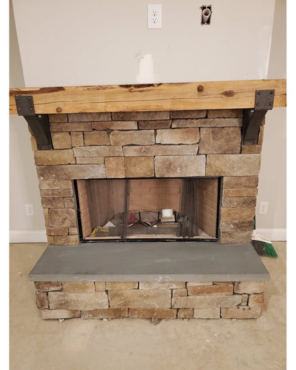 Rustic stone fireplace with wooden mantel supported by black steel Clermont brackets with rivets, showing Industrial Farm ...