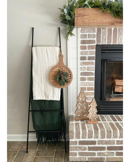 Black metal Tapered Michael Farmhouse Ladder by Industrial Farm Co displaying white knit throw and green blanket near bric...