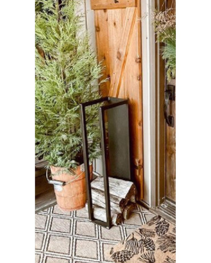 Black metal Toby Firewood Holder by Industrial Farm Co displayed on patterned tile patio with terracotta plant pot and wov...