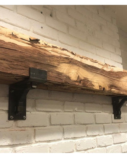 Rustic reclaimed wood mantel mounted on white brick fireplace using black Buffalo 4-inch steel brackets with square suppor...