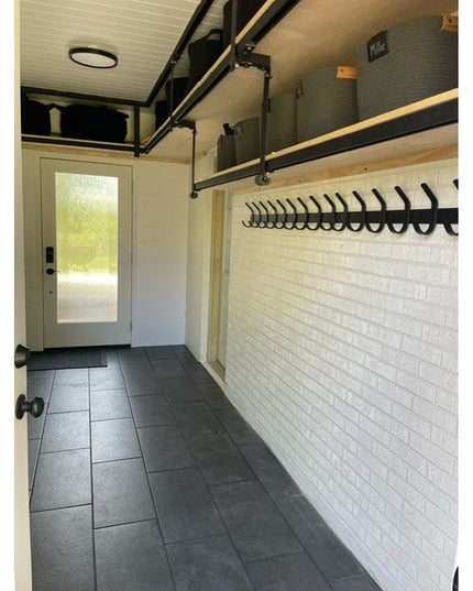 Industrial Farm Co Christopher Double Hook black metal coat rack mounted on white brick wall in modern mudroom entryway